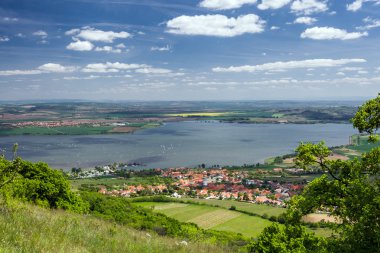 lente platteland met dorp, lake, blauwe hemel en wolken