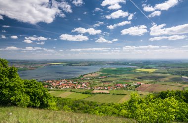 lente platteland met dorp, lake, blauwe hemel en wolken