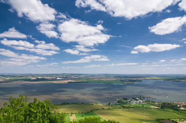 Campo de primavera con lago, campos y cielo azul con nubes —  Fotos de Stock