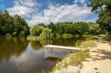 Path around pond with wooden pier in summer landscape - Czech Republic, Europe.