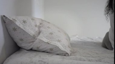 Bunalımdaki kadın kendini yatağa atıyor ve battaniyenin altına saklanıyor.