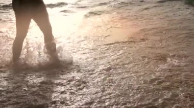 Deniz dalgalarında yürüyen ve su sıçratan kadın ağır çekim