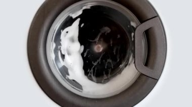 Evde çamaşır makinesinde çamaşır yıkamak. Dönen davul çamaşır makinesinin yakın çekim videosu.