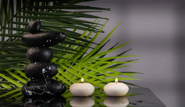 zen stones and candles with green leaves