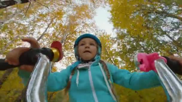 Portret wesołej dziewczynki w kasku jeździ rowerem po lesie, POV — Wideo stockowe