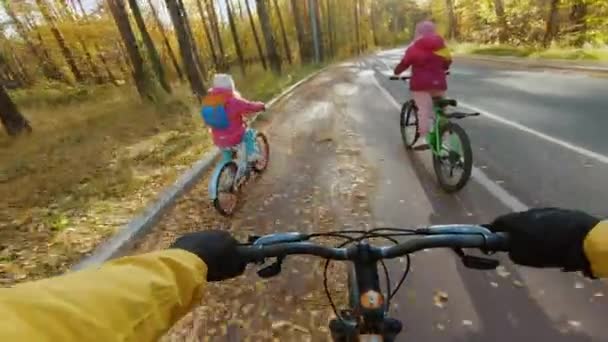 Far med sina döttrar har en cykeltur i höstparken, POV utsikt — Stockvideo