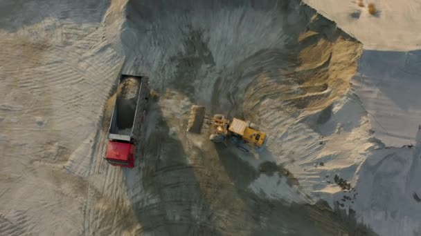 Εμπρός φορτωτής φόρτωση συνθλιβεί πέτρα σε χωματερή φορτηγό στο λατομείο, εναέρια κορυφή προς τα κάτω — Αρχείο Βίντεο