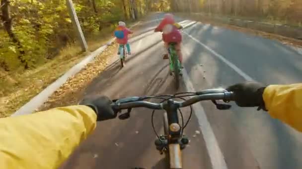 Pai com suas filhas têm um passeio de bicicleta no parque de outono, vista POV — Vídeo de Stock