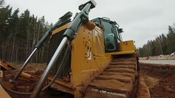 Гусеничний бульдозер з рівнем леза землі, будівництво нової дороги — стокове відео