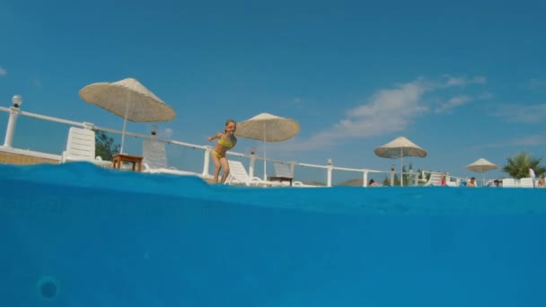 Дві маленькі дівчата стрибають у басейн. Діти у відпустці на тропічному курорті — стокове відео