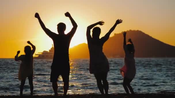 Σιλουέτα χαρούμενων οικογενειακών χορών, παίζοντας και διασκεδάζοντας στην παραλία το ηλιοβασίλεμα — Αρχείο Βίντεο