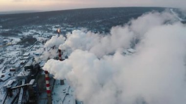 Kışın sanayi bölgesi, fabrika bacası tüttürüyor. Borular atmosferi kirletir