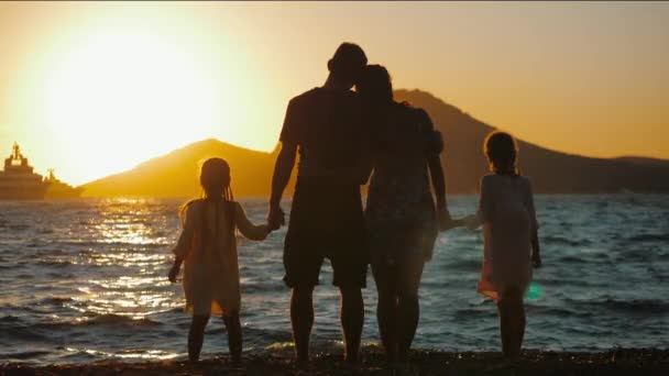 Silhuett av lycklig familj stående på stranden vid solnedgången och kramas Videoklipp