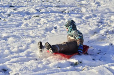 Tepeden aşağı kızakla bir çocuk
