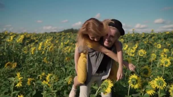 Zrzavá fenka na slunečnicovém poli, která si užívá, točí se, objímá se s chlapem — Stock video