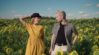Ayçiçeği tarlasında kızıl saçlı kadınlar telefondaki şapkalı adamın üzerinde fotoğraflanır.