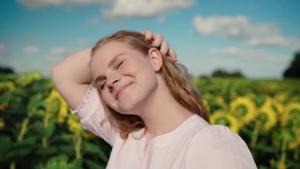 Jovem loira caucasiana menina no campo de girassol sorrisos, endireitar o cabelo encaracolado — Vídeo de Stock