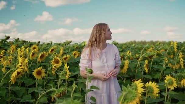 Mladá blondýnka kavkazský dívka v slunečnice pole úsměvy, narovnat kudrnaté vlasy — Stock video
