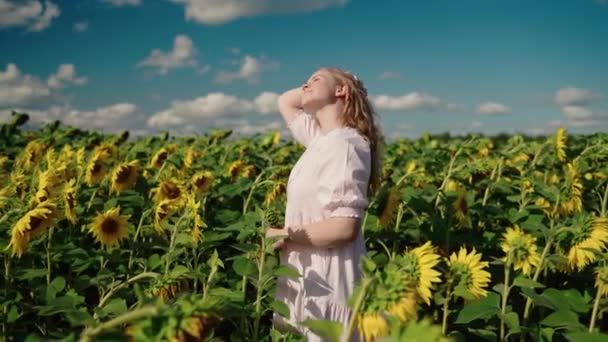 Young blonde caucasian girl in sunflower field smiles, straighten curly hair — Stock Video