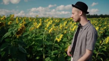 Ayçiçeği tarlasında piercing takmış genç bir adam telefon kamerasında selfie çekiyor.