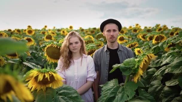 Pasangan Kaukasia berpose di kamera dalam bidang bunga matahari pada hari yang cerah — Stok Video