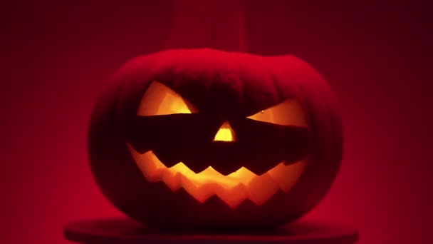 Dynia halloween z oświetleniem dinamik na platformie, czerwone tło — Wideo stockowe