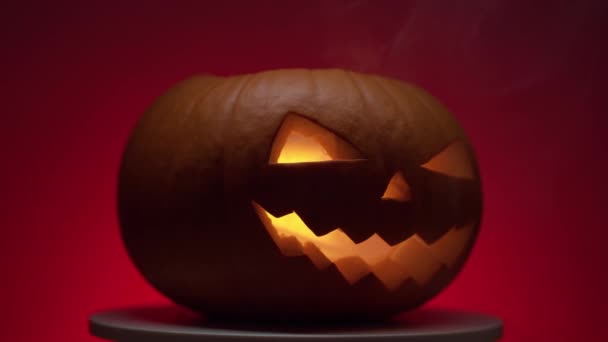 Halloween pumpkin with dinamik light on rotating platform, red background — Stock Video