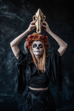 Boynuzlu cadı bir kurdun kafatasını kaldırır ve gözlerini yuvarlar.