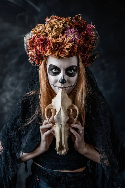 Halloween-Hexe mit aufgenähtem Mund, Hörnern, Totenkopf in einem dunklen Raum, zaubert — Stockfoto