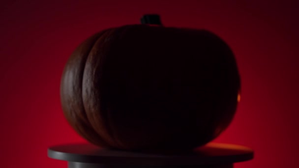 Calabaza de halloween con luz dinamik en la plataforma giratoria, fondo rojo — Vídeo de stock