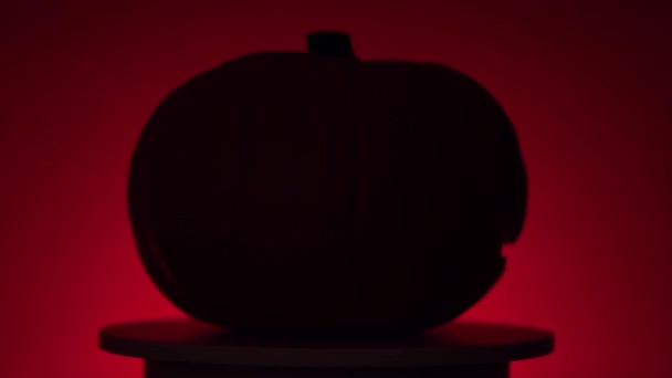 Хеллоуїн гарбуз з динаміком світла на обертовій платформі, червоний фон — стокове відео