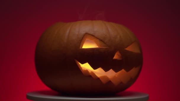 ハロウィーンのカボチャにダイナミクの光が回転プラットフォームに赤い背景に — ストック動画