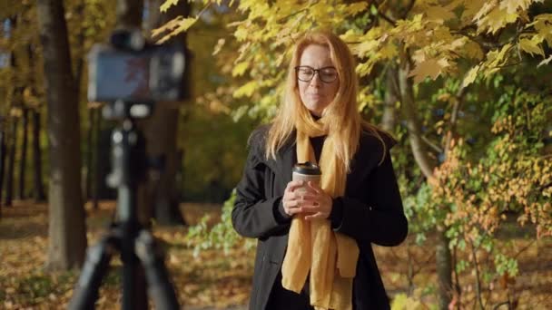 Portret van een jonge vrouw met lang rood haar en heldere make-up in een herfstpark — Stockvideo