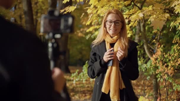 Videographer records on camera report from women woman with glasses in park — Stock Video