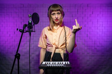 woman singer in recording studio with microphone, keys showing gesture fuck clipart