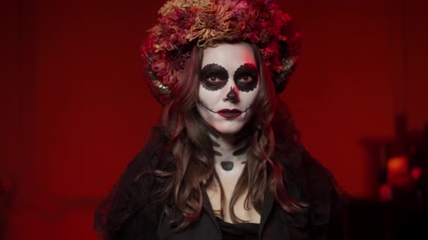 Vrouw in Calavera-stijl afbeelding op halloween in kamer met rood licht van kampvuur — Stockvideo