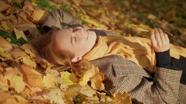美しい目をした女性は葉に息を吹きかけカメラを覗き込み. — ストック動画