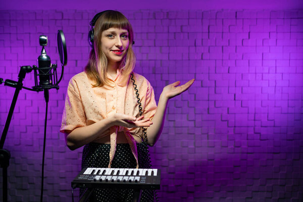 woman singer in headphones in recording studio with microphone, synthesizer