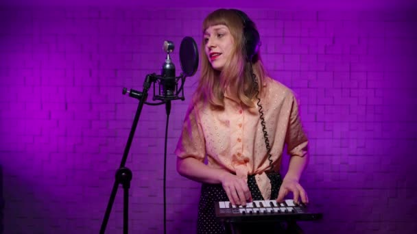 Kvinnlig sångare i studio monitor hörlurar spelar nycklar, poster i mikrofon — Stockvideo