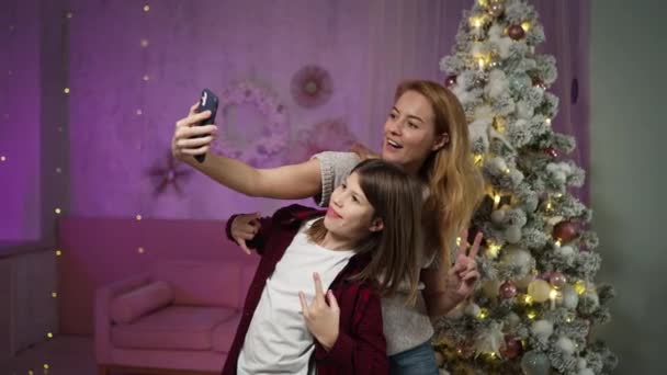 Mother takes selfie on phone with teenage son on Christmas Eve in festive room — Stock Video