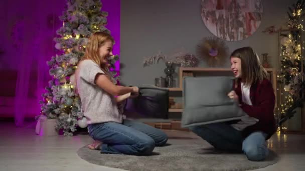 Mãe com o filho adolescente lutando travesseiros na véspera de Ano Novo decorado sala de estar — Vídeo de Stock