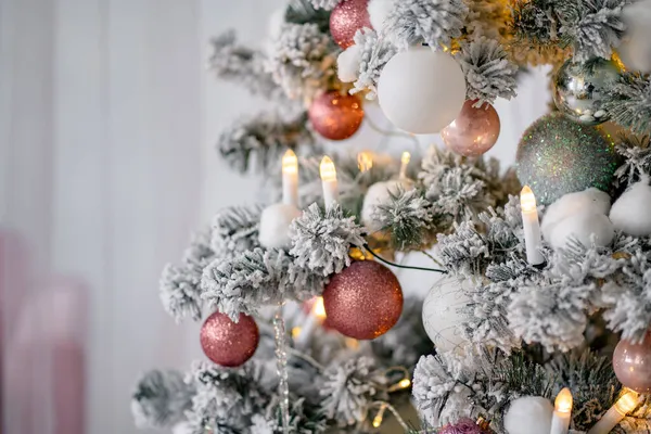 Primer plano del árbol de Navidad nevado, bolas decoradas, guirnalda, velas, bolas de nieve —  Fotos de Stock