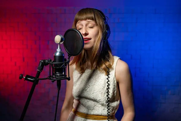 Cantante mujer en auriculares realiza canción de todo corazón. Micrófono con filtro pop — Foto de Stock