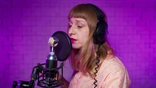 Певица в студии звукозаписи поет песню в микрофон с поп-фильтром — стоковое видео