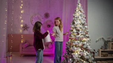 Uzun saçlı adam annemin Noel ağacını süslemesine yardım ediyor, yılbaşı gecesi balo veriyor.