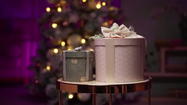 Kerstcadeaus op een tafel in een feestelijke woonkamer met lichtjes op oudejaarsavond — Stockvideo