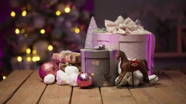 Concepto de año nuevo. Regalos sobre mesa de madera sobre el fondo del árbol de Navidad — Vídeos de Stock