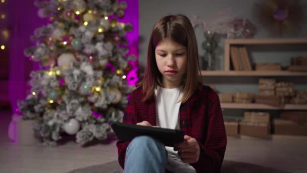 Adolescente em treinamento on-line com tablet. Árvore de Natal na véspera de Ano Novo — Vídeo de Stock