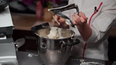 Pasta şefi, profesyonel mikserden spatulayla krema çıkartıyor.