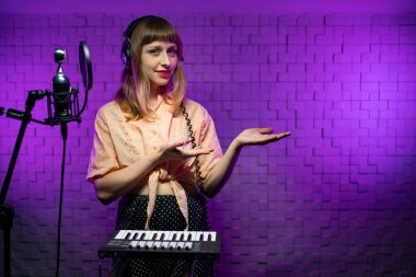 woman singer in headphones in recording studio with microphone, synthesizer clipart